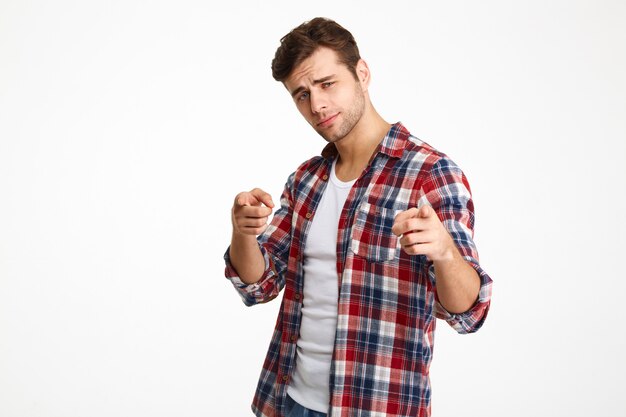 Close-upfoto van ernstige jonge kerel in geruit overhemd dat met twee vingers richt