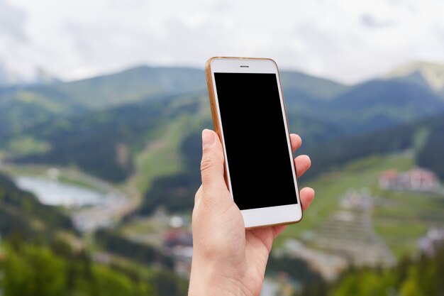 Close-upfoto van onbekende handholding geschakelde smartphone met het lege scherm