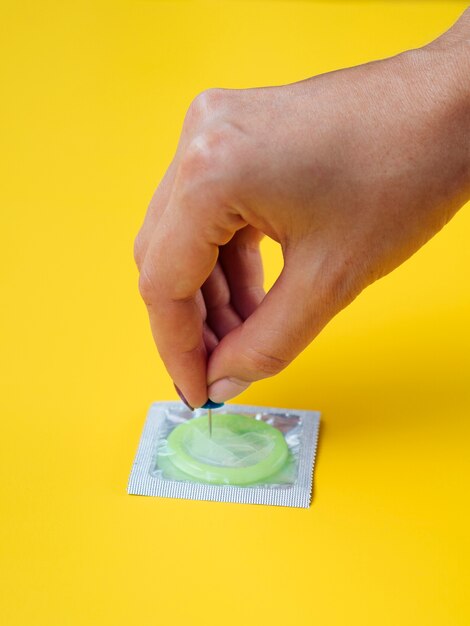 Close-uphand die een condoom met een speld steken