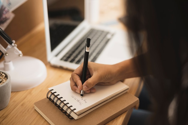 Close-uphand die op een notitieboekje schrijven