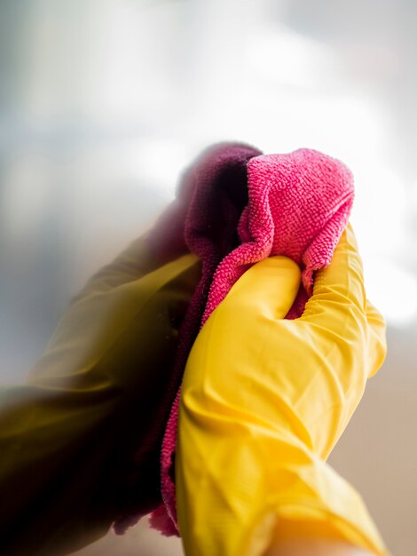 Close-uphand met het rubberen handschoen desinfecteren