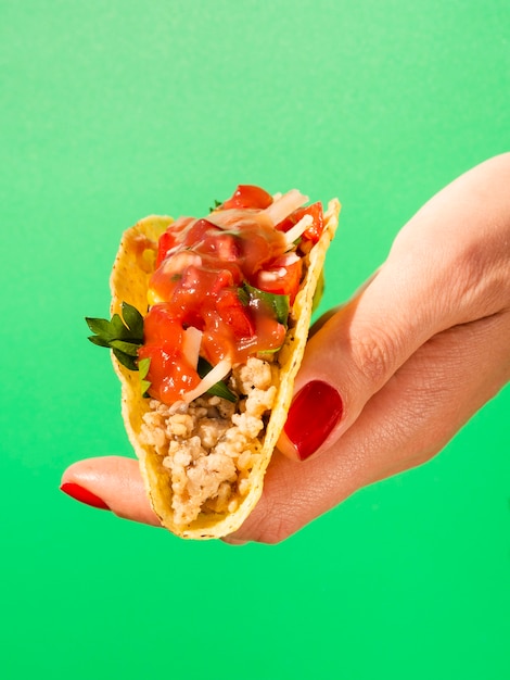 Close-uphand met taco en groene achtergrond