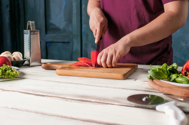 Close-uphand van chef-kokbakker die pizza maken bij keuken