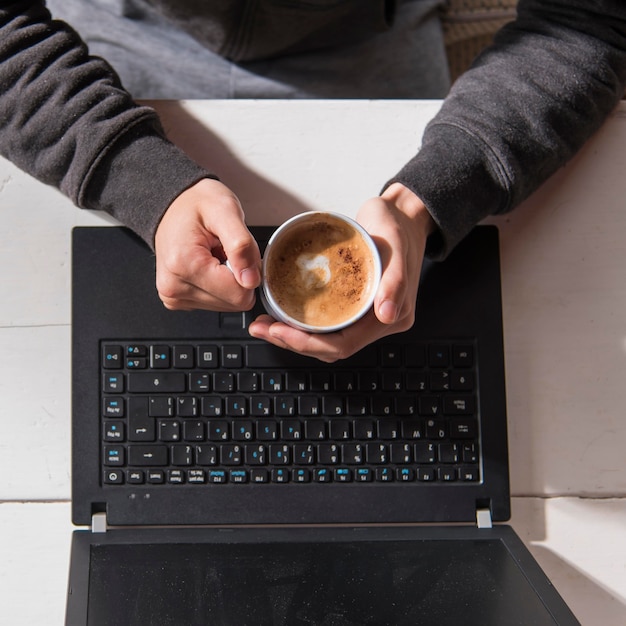 Gratis foto close-uphanden die koffiekop houden