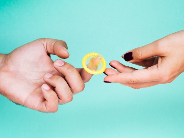 Close-uphanden met onverpakt geel condoom