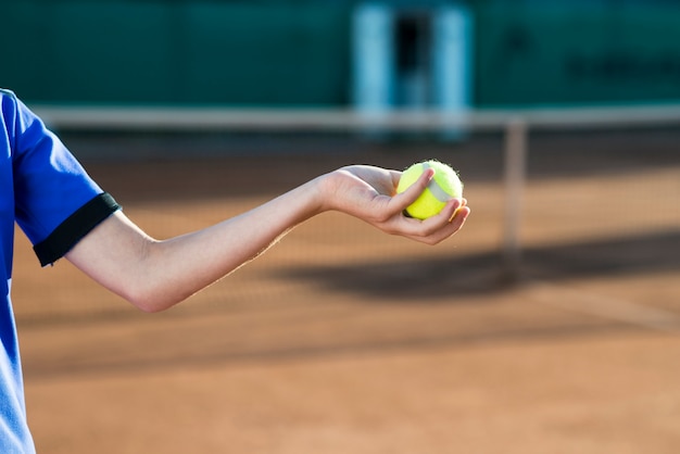 Close-upjong geitje die een tennisbal in hand houden