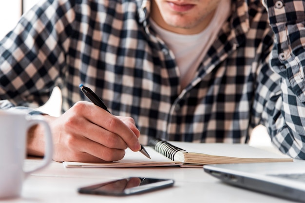 Close-upkerel die op notitieboekje schrijven