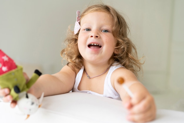 Gratis foto close-upmeisje met lolly en stuk speelgoed