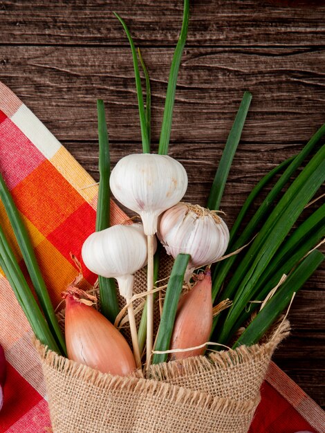 Close-upmening van boeket van groenten als knoflook groene ui en sjalot op doek op houten achtergrond