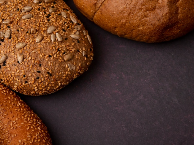 Close-upmening van brood als gezaaid bruin en klassiek maïskolfongezuurde broodje op kastanjebruine achtergrond met exemplaarruimte