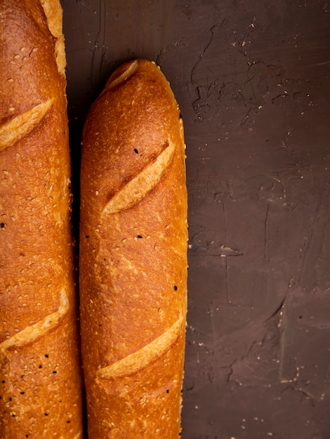 Gratis foto close-upmening van franse baguettes op kastanjebruine achtergrond met exemplaarruimte