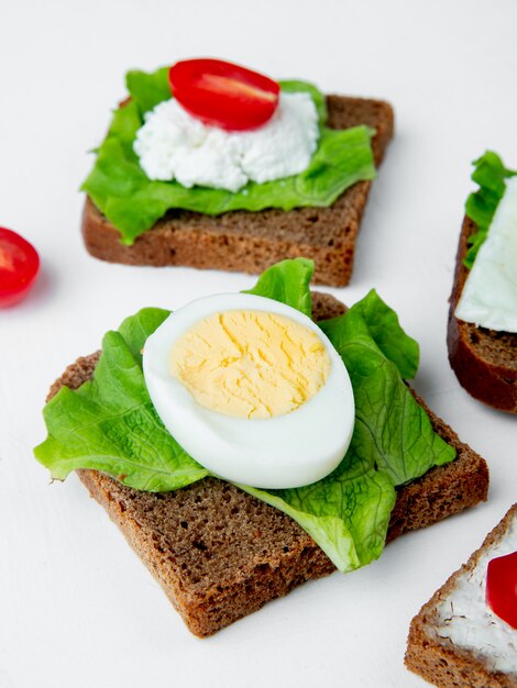 Close-upmening van groenten als gekookt ei en spinazie op brood op witte achtergrond