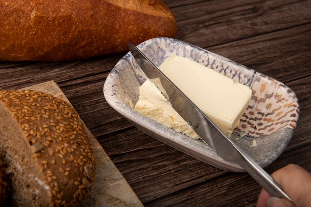 Close-upmening van kinfe scherpe boter en brood rond op houten achtergrond