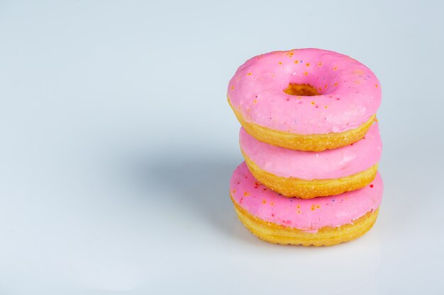 Close-upod roze donuts surves op witte muur.