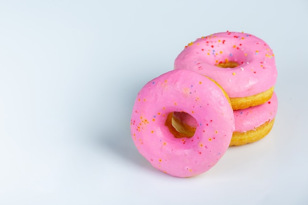 Close-upod roze donuts surves op witte muur.