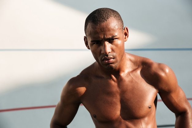 Close-upportret van de ernstige vermoeide knappe mens van afro Amerikaanse sporten, die na training op stadion rusten