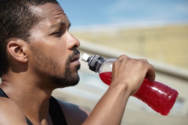 Close-upportret van de jonge mens die zelf hydrateert