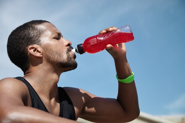 Close-upportret van de jonge mens die zelf hydrateert