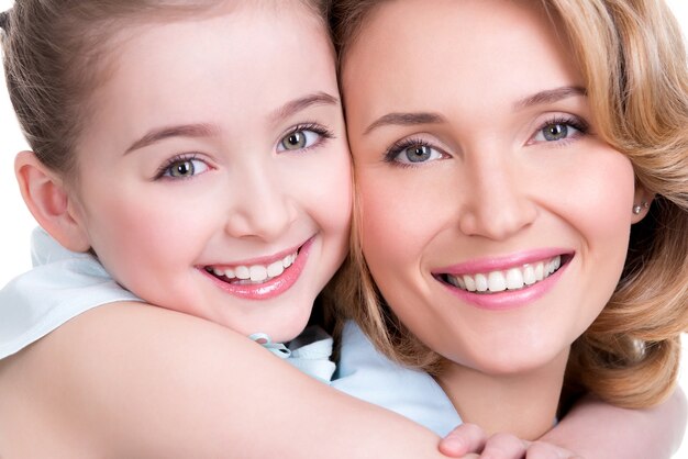 Close-upportret van gelukkige witte geïsoleerde moeder en jonge dochter -