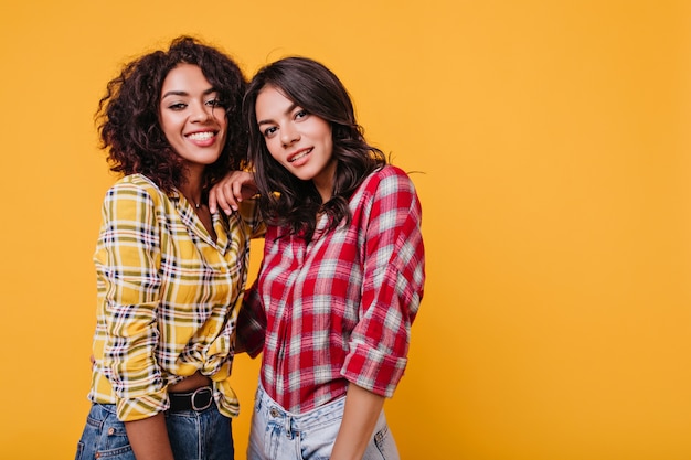 Close-upportret van jonge vrouwen in geruite overhemden. Meisjes met bruine ogen glimlachen schattig.