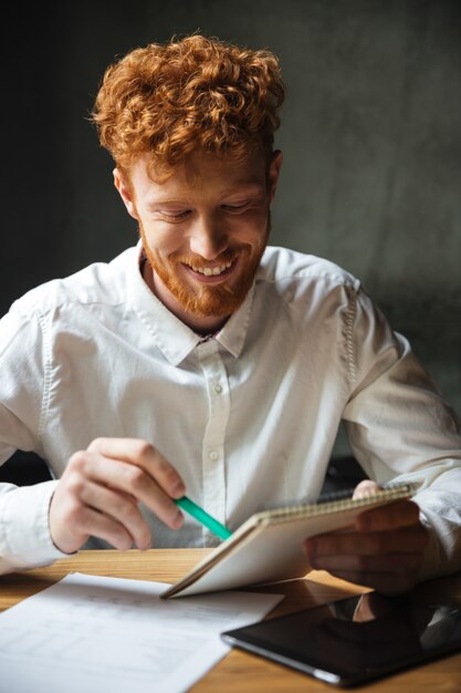 Close-upportret van knappe glimlachende student die thuis bestuderen