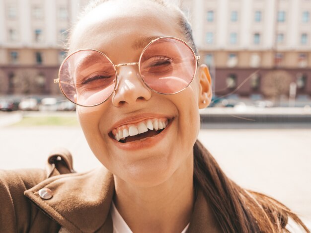 Close-upportret van mooi glimlachend donkerbruin meisje in de zomer hipster jasje. Model nemen selfie op smartphone.