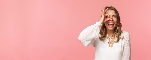 Close-upportret van perfect knap blond meisje in witte kleding die door ok teken en smil . kijken