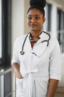 Close-upportret van vriendelijke, glimlachende zelfverzekerde vrouwelijke zorgverlener met laboratoriumjas, stethoscoop. geïsoleerde ziekenhuis kliniek achtergrond. tijd voor een kantoorbezoek