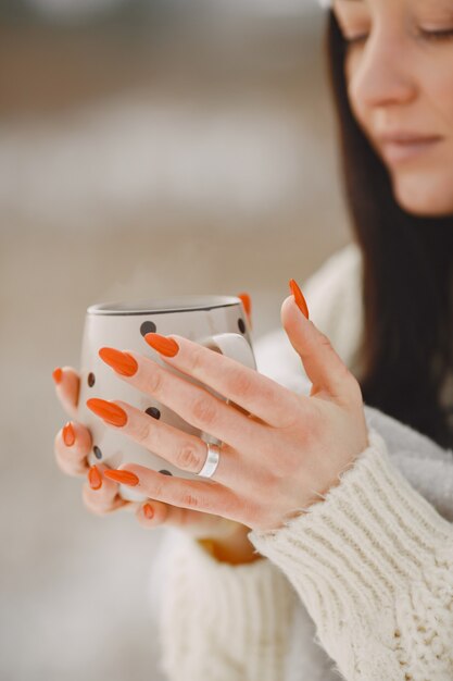 Close-upportret van vrouw in witte sweater met thee