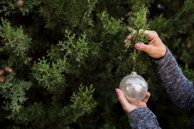 Close-upvrouw die de Kerstmisboom met bol verfraaien