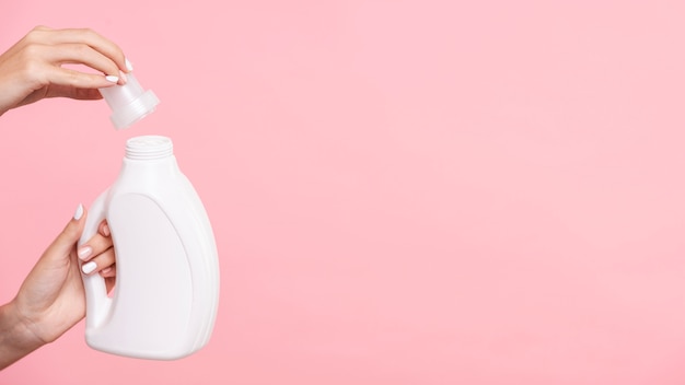 Close-upvrouw die detergent fles openen