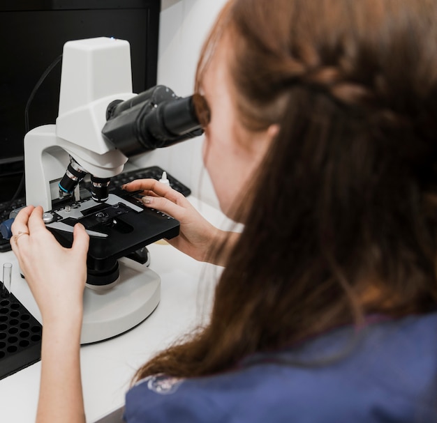 Close-upvrouw die door microscoop kijken