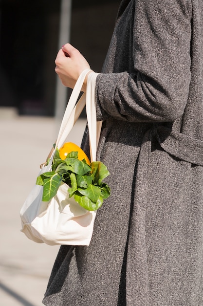 Close-upvrouw die ecologische zak met groenten dragen