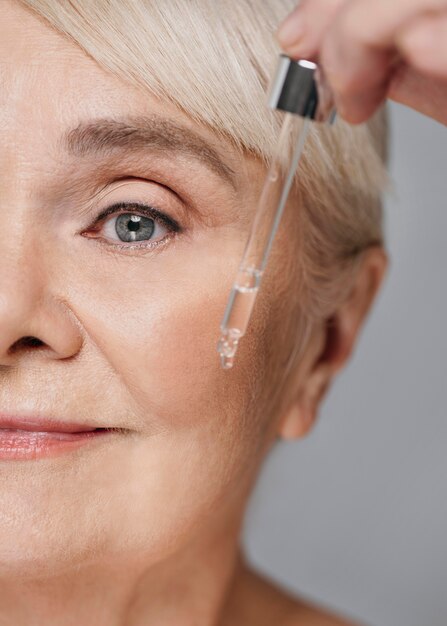 Close-upvrouw die gezichtsserum gebruikt