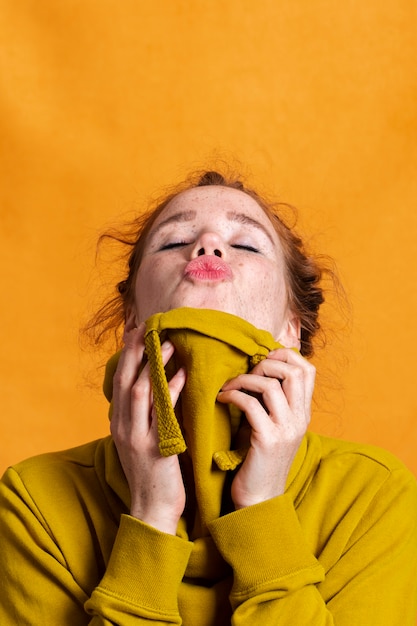 Close-upvrouw met gele hoodie en oranje achtergrond