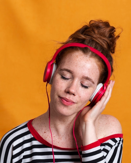 Close-upvrouw met hoofdtelefoons en oranje achtergrond