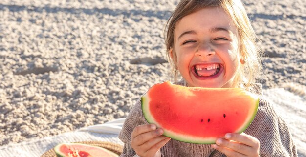 Closeup klein meisje eet watermeloen op het strand