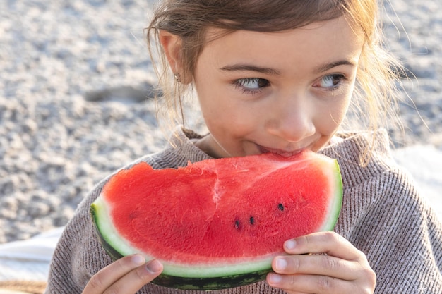 Gratis foto closeup klein meisje eet watermeloen op het strand