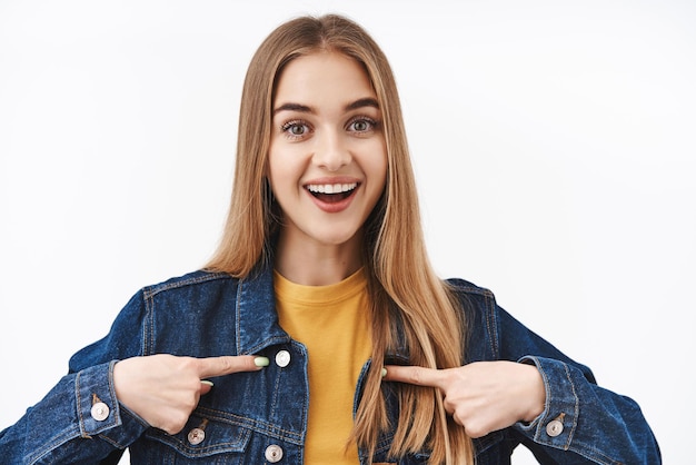 Closeup portret excted en gelukkig schattige jonge vrouw met blond haar vragen om lid te worden willen deelnemen zichzelf wijzend op de borst en glimlachend beste kandidaat voor baan witte achtergrond