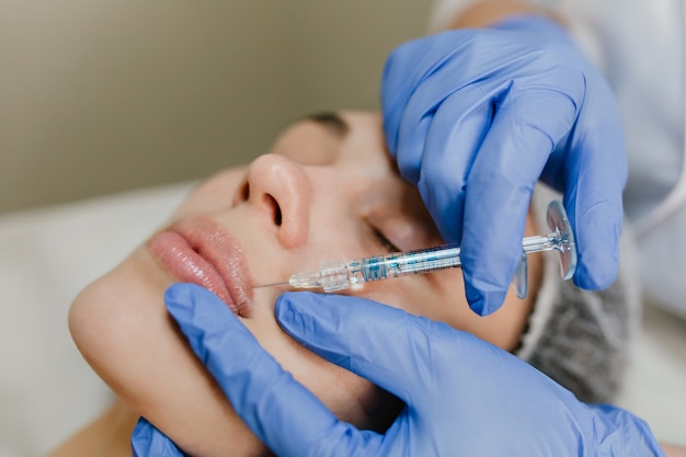 Closeup portret injectie op lippen van mooie vrouw tijdens botox procedures in salon. Professioneel werk, verjonging, moderne geneeskunde, schoonheid maken, gezondheidszorg