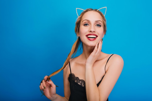 Closeup portret van lachende jonge mooie vrouwen genieten van zichzelf op feestje, poseren. Het dragen van een zwarte jurk en een hoofdband met kattenoren.