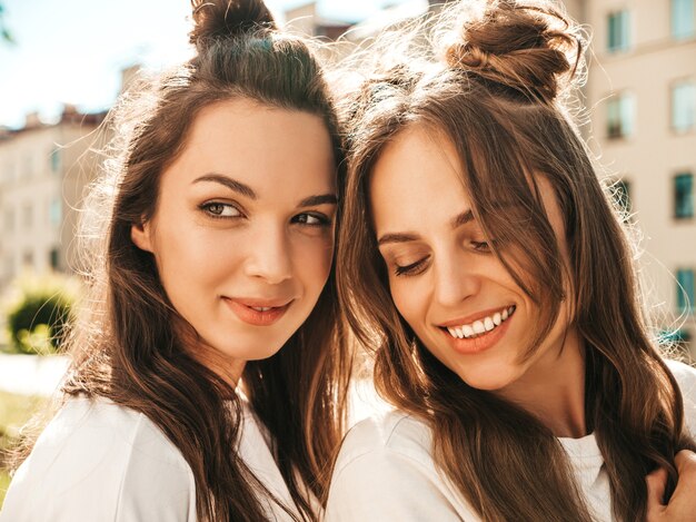 Closeup portret van twee jonge mooie lachende hipster vrouw in trendy zomer witte t-shirt kleding