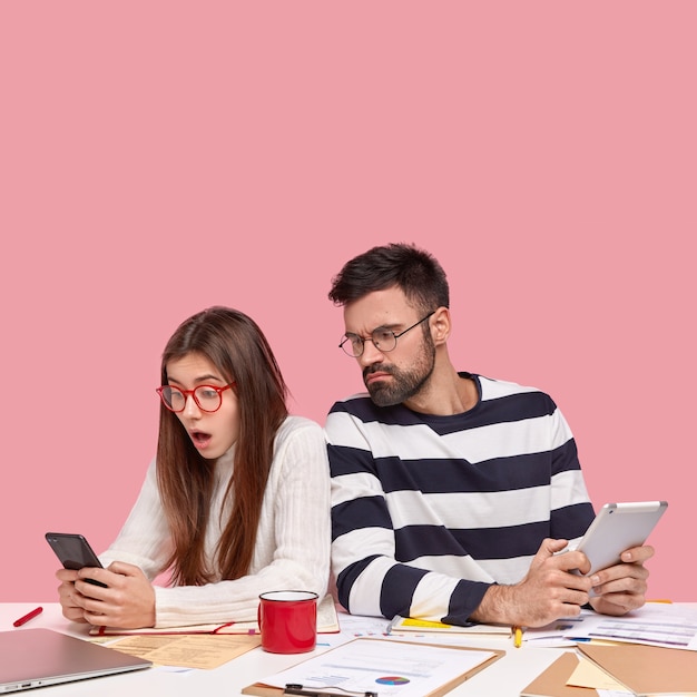 Collega's die aan bureau met documenten en gadgets zitten