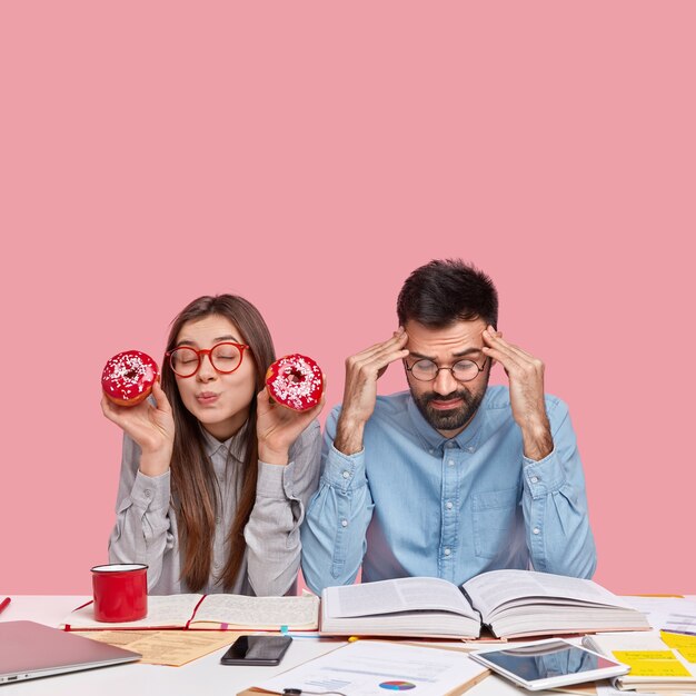 Collega's die aan bureau met documenten en gadgets zitten