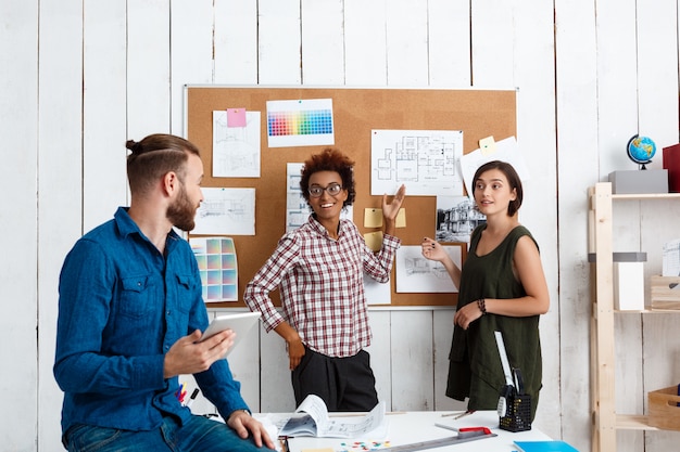 Collega's die glimlachen, spreken en tekeningen bespreken