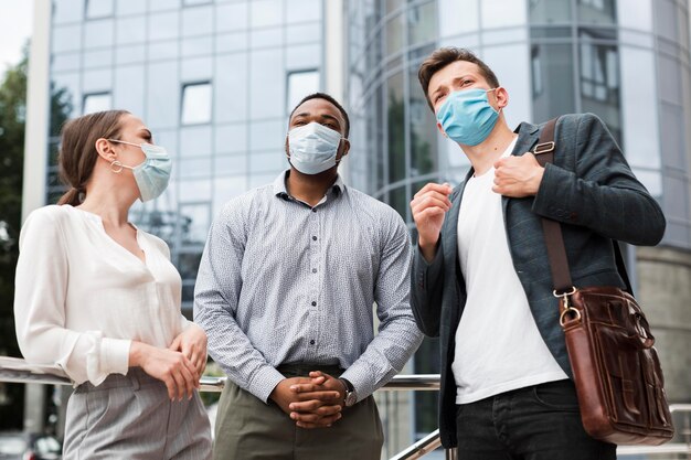 Collega's die tijdens een pandemie buiten chatten terwijl ze medische maskers dragen
