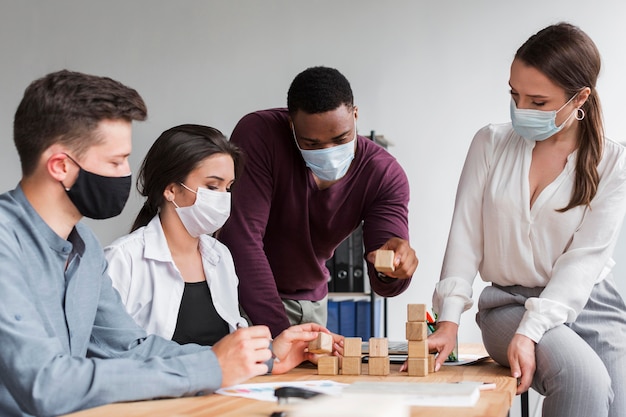 Collega's die tijdens een pandemie op kantoor vergaderen met medische maskers op