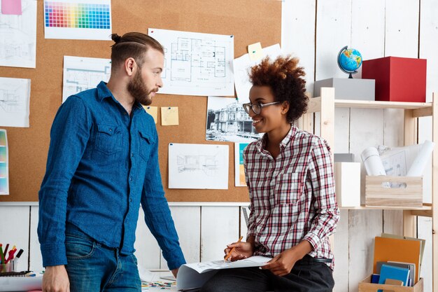 Collega's glimlachen, spreken, bespreken tekeningen, nieuwe ideeën