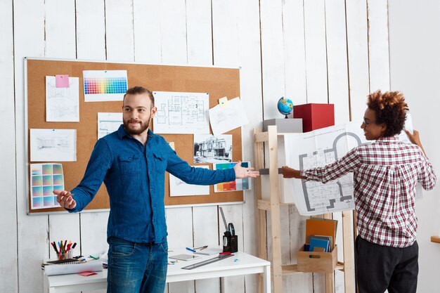 Collega's glimlachen, spreken, bespreken tekeningen, nieuwe ideeën