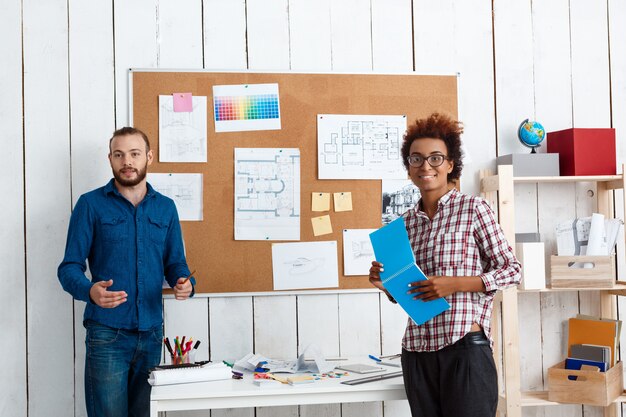 Collega's glimlachen, spreken, bespreken tekeningen, nieuwe ideeën